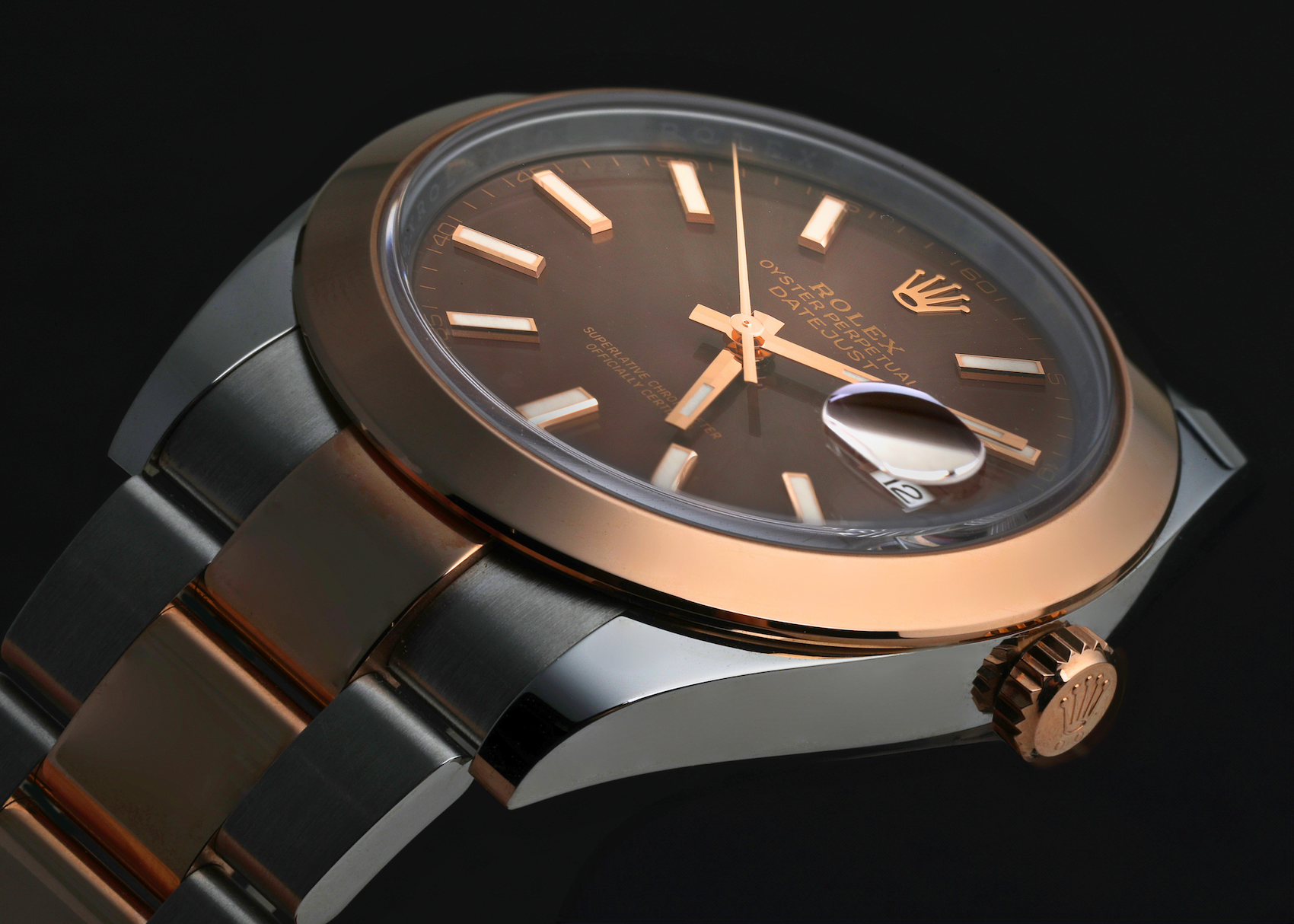 Close-up of a two-tone Rolex Datejust with a chocolate brown dial and luminous baton hour markers.