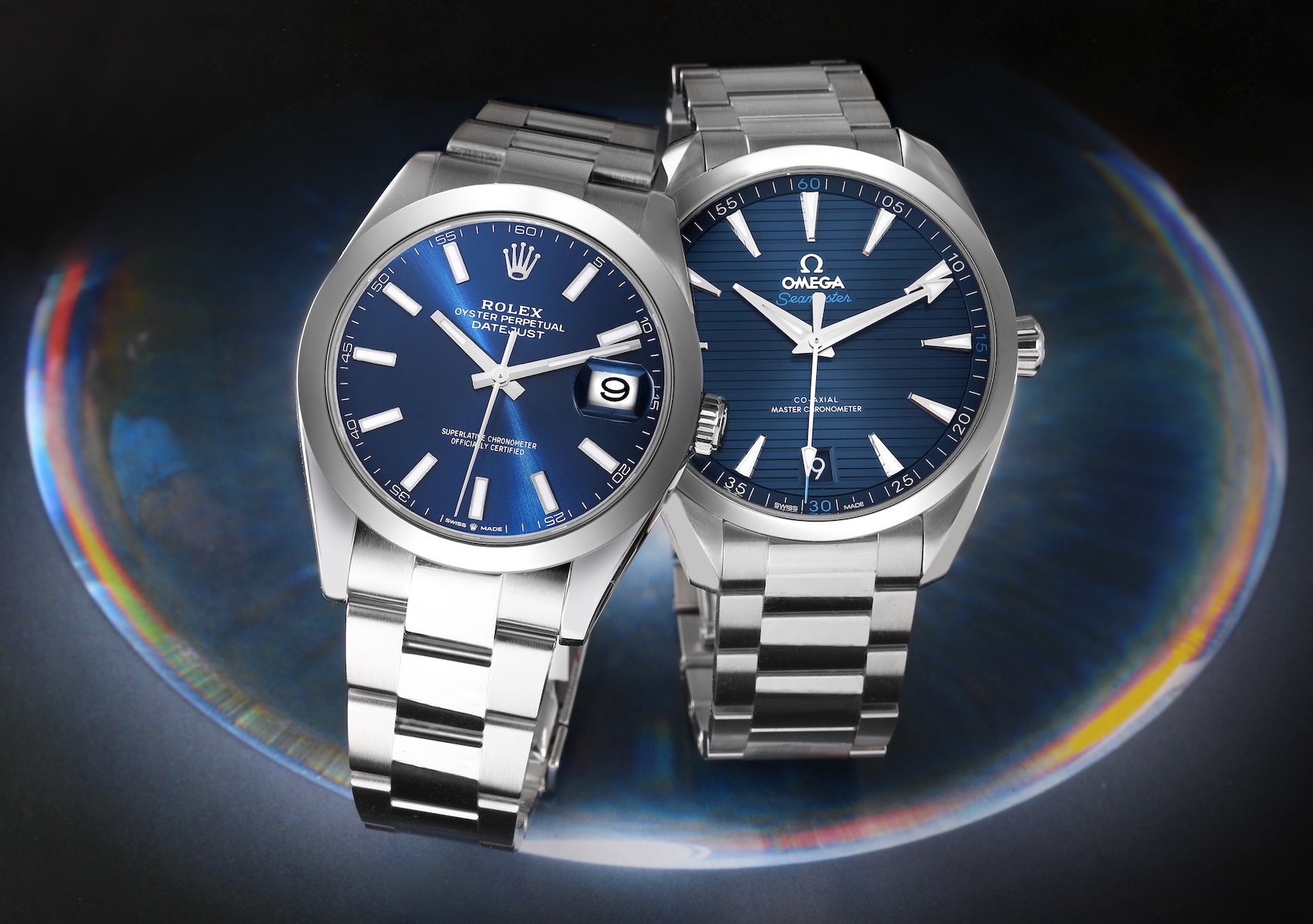 Side-by-side comparison of a stainless steel Rolex Datejust with a blue dial and an Omega Seamaster Aqua Terra with a blue teak dial.