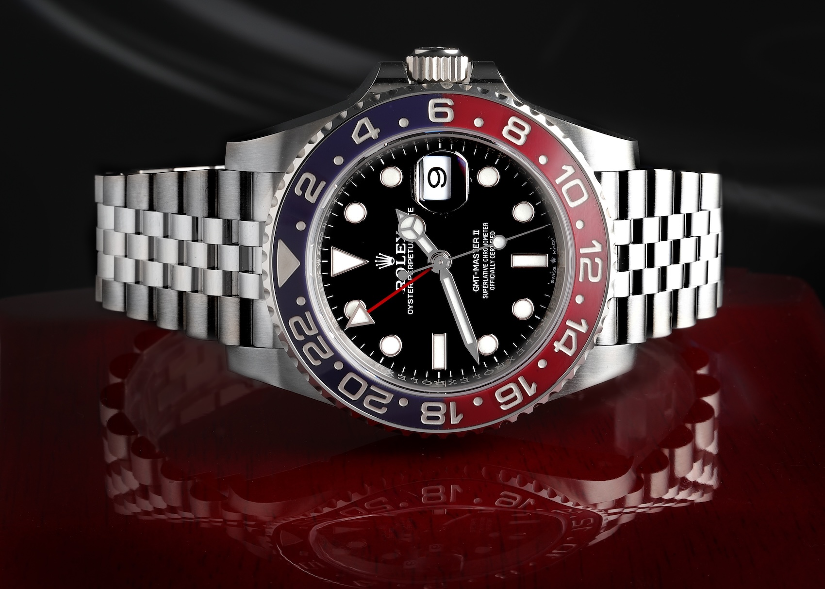 Close-up of the Rolex GMT-Master II Pepsi 126710BLRO resting on a glossy red surface, highlighting the red and blue ceramic bezel.