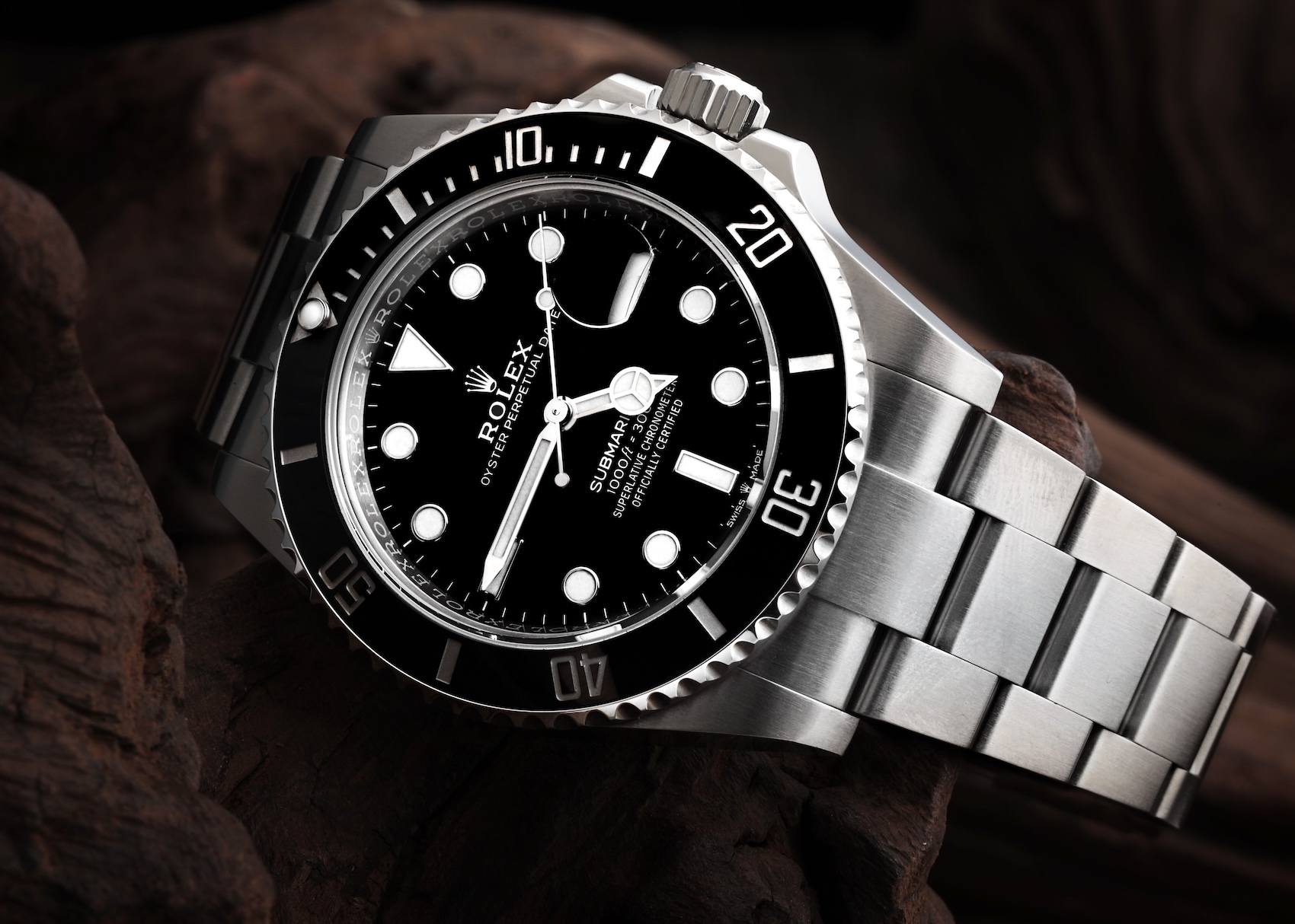 Close up of a Rolex Submariner Date reference 126610 in Oystersteel with a black dial and ceramic bezel resting on dark wood.