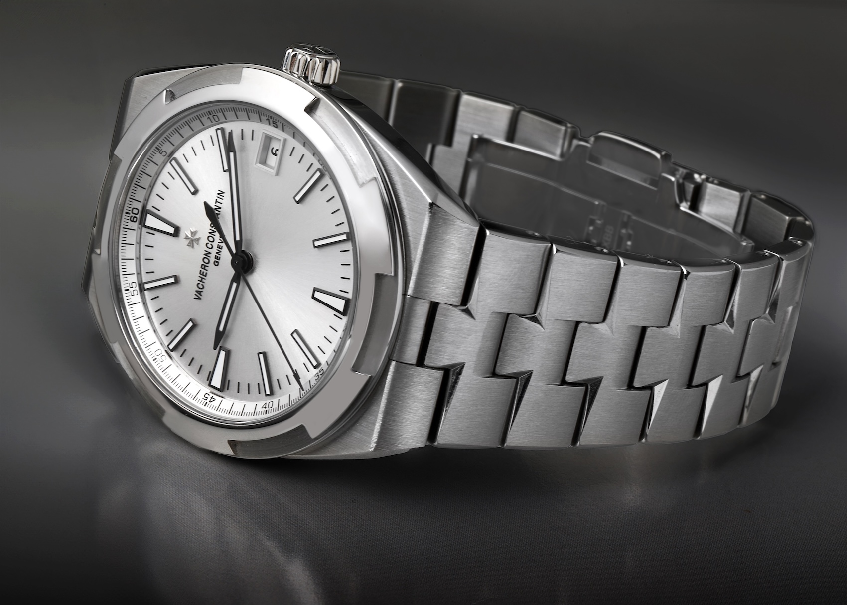 Oblique profile view of a Vacheron Constantin Overseas steel watch, showcasing the gapless flow of the case into the integrated stainless steel link bracelet.