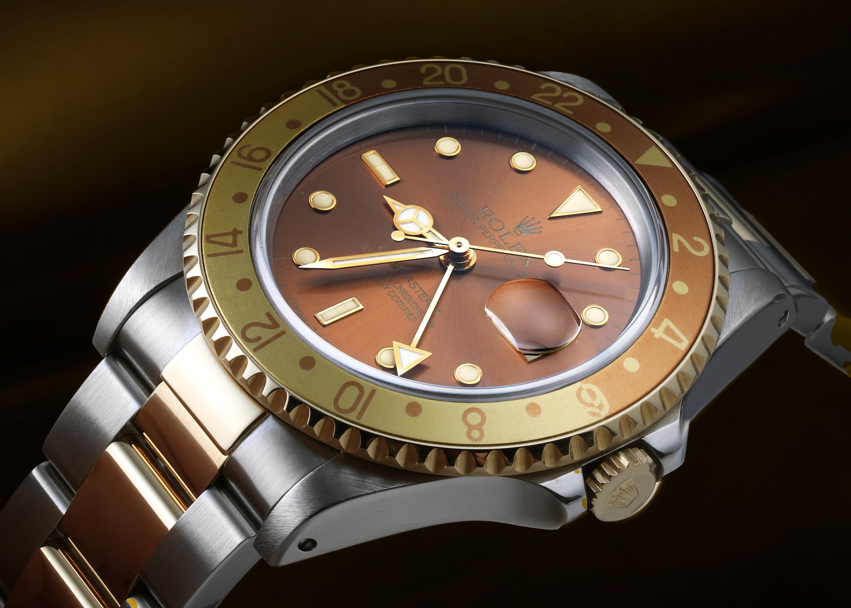 Close-up shot of a neo-vintage two-tone Rolex GMT-Master II reference 16713 with a sunburst brown dial, gold hands, and a brown and gold aluminum bezel insert.