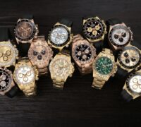 A high-contrast collection of luxury gold Rolex Daytona chronographs on black Oysterflex bracelets, featuring various dials.