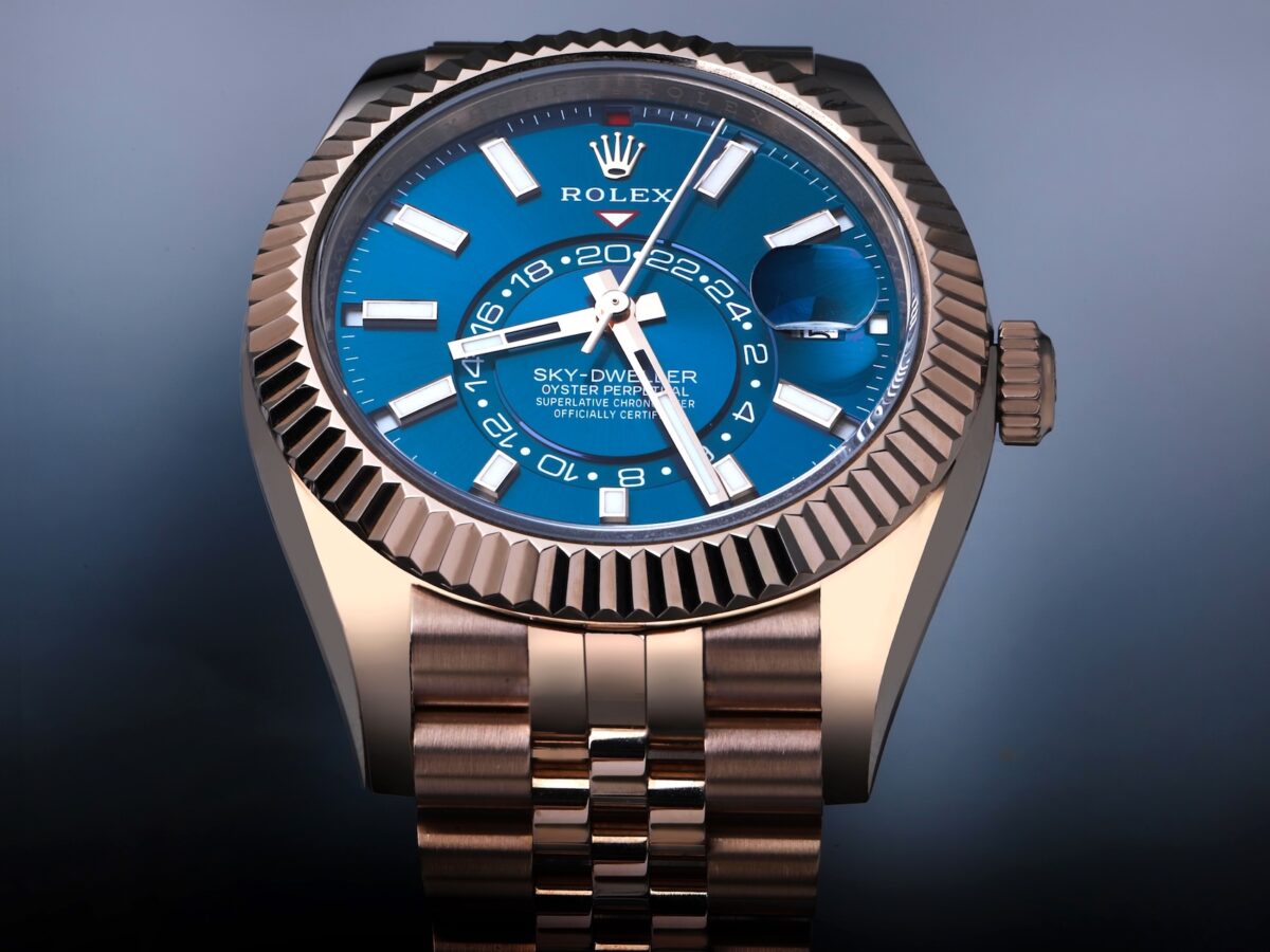 A front-on professional studio shot of the Rolex Sky-Dweller Ref. 336935 in Everose Gold. The watch features the specific teal (blue-green) dial and is fitted with a Jubilee bracelet. The fluted bezel, 24-hour disc, and date display are perfectly clear.
