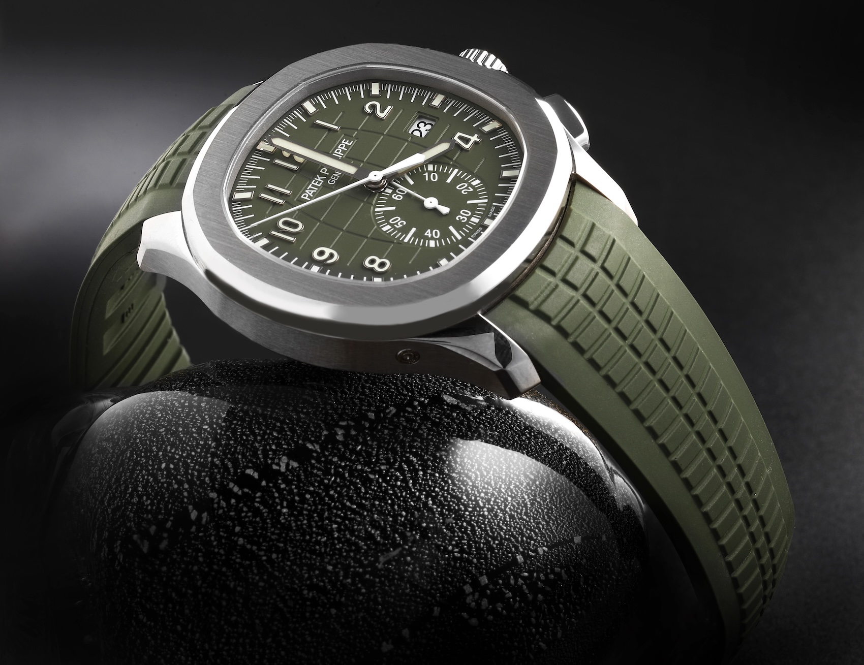 Profile view of the white gold Patek Philippe Aquanaut Chronograph 5968G resting on a stone base, highlighting the khaki green dial and flyback pushers.