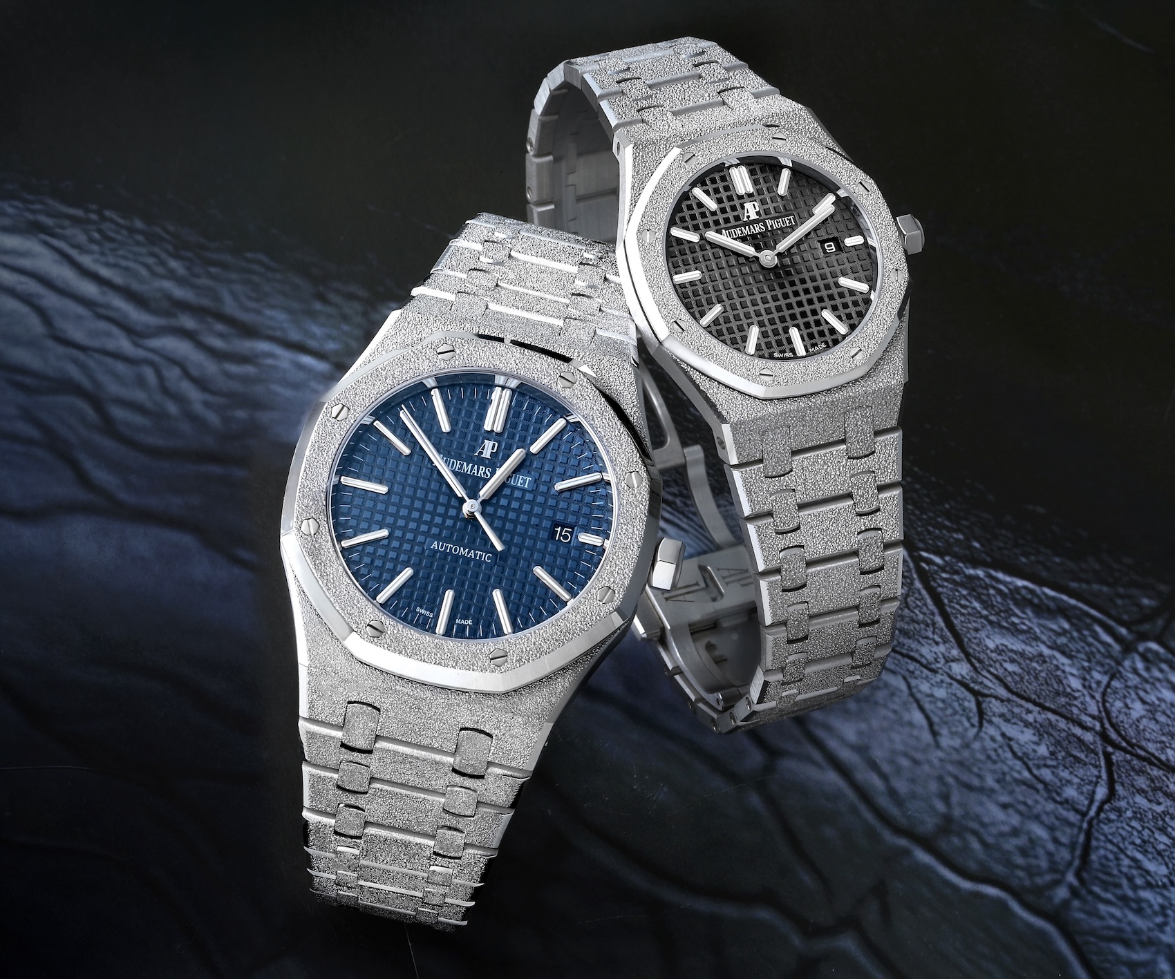 Two Audemars Piguet Royal Oak Frosted Gold watches crafted in 18k white gold, displaying both blue and black Grande Tapisserie dials. 