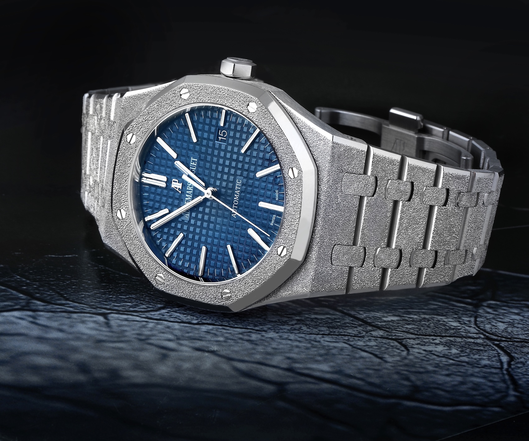 A landscape-oriented feature of the Audemars Piguet Royal Oak Frosted Gold watch in 18k white gold, showcasing the hammered finish and a blue Grande Tapisserie dial.
