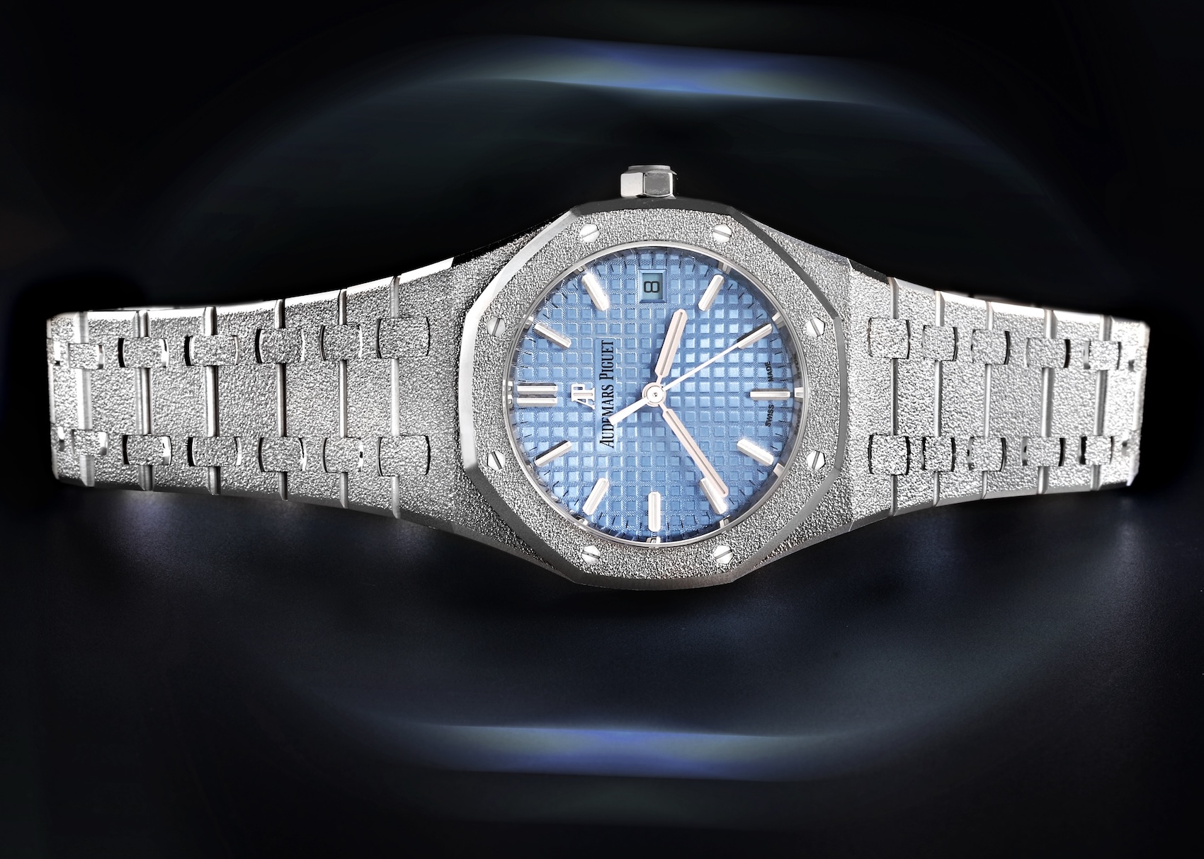 A landscape view of the Audemars Piguet Royal Oak Frosted Gold reference 77353BC in 18k white gold, showcasing the Florentine hammered finish and a light blue Grande Tapisserie dial. 