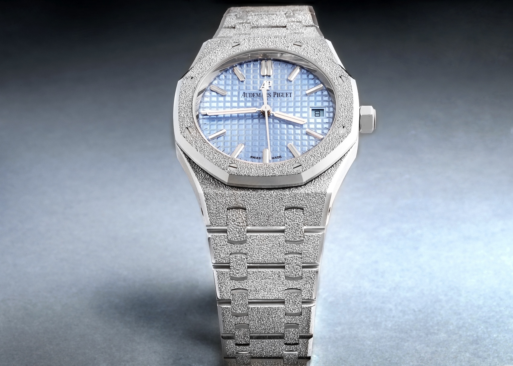 An upright, full-bracelet view of the Audemars Piguet Royal Oak Frosted Gold reference 77353BC in 18k white gold, featuring a light blue Grande Tapisserie dial. 