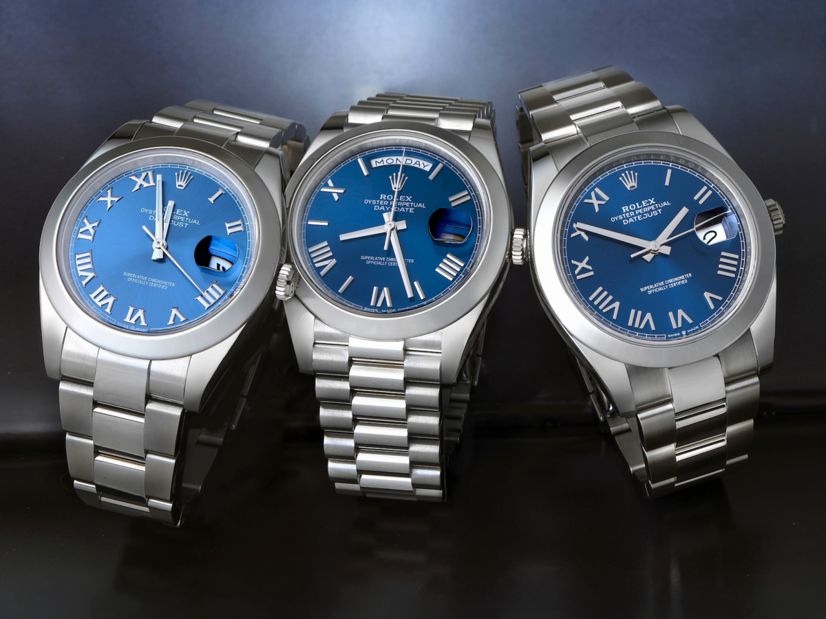 Group of three Rolex watches featuring blue dials with deconstructed Roman numerals, including stainless steel Datejust and Day-Date models.