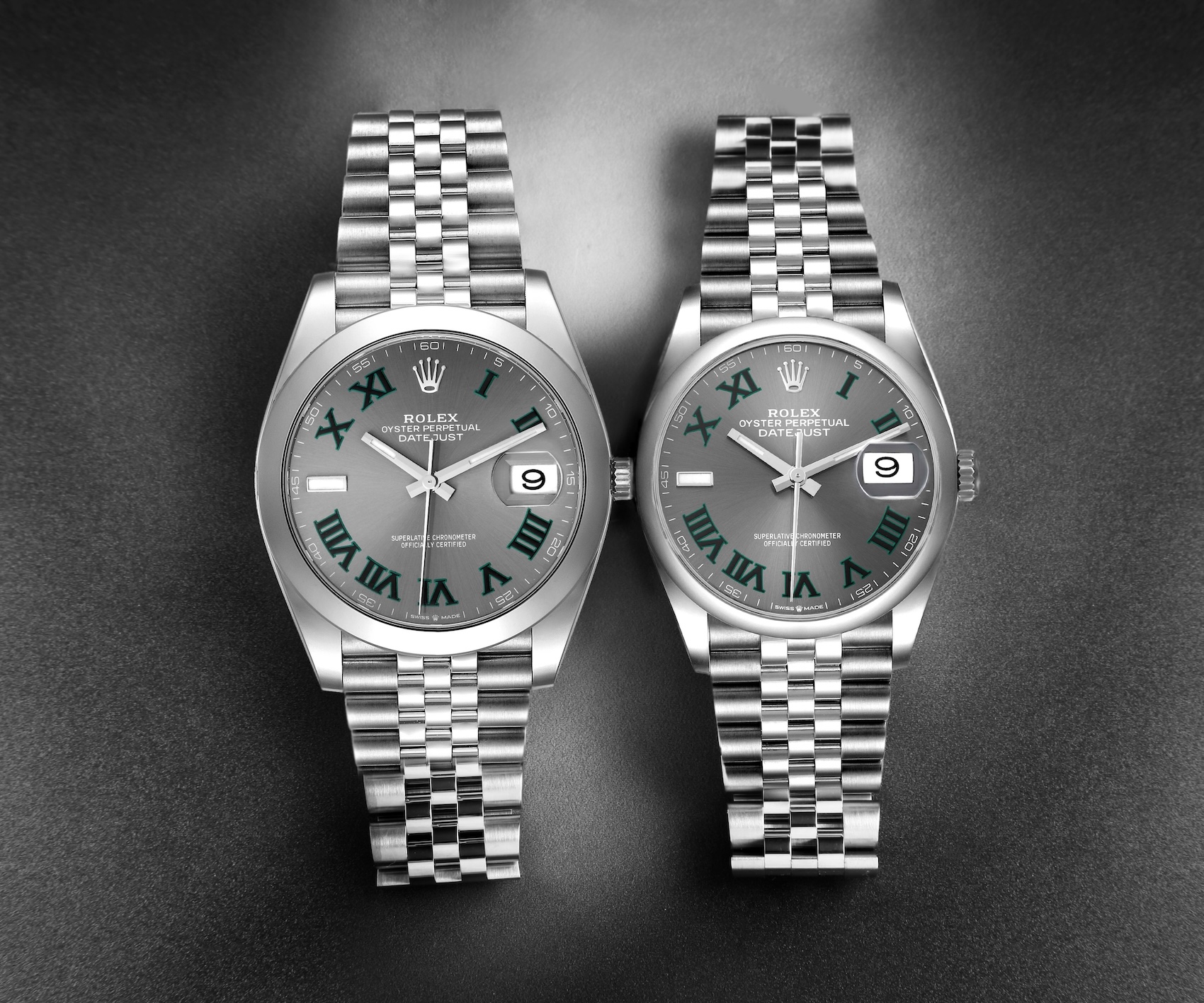 Two stainless steel Rolex Datejust watches side-by-side featuring the Wimbledon dial with a slate grey background, green-outlined Roman numerals, and a luminous 9 o'clock marker.