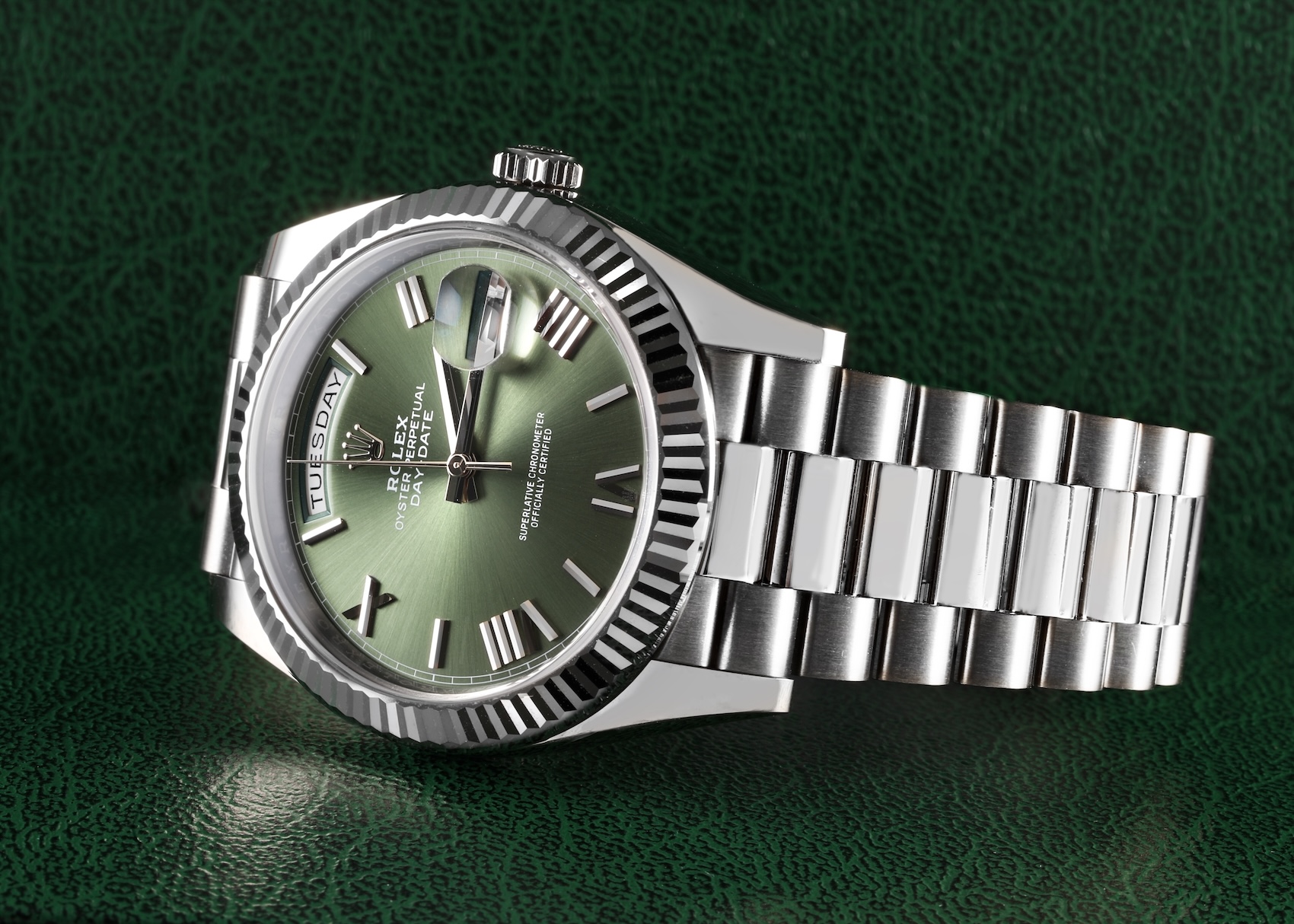 White gold Rolex Day-Date 40 reference 228239 featuring a fluted bezel and an olive green dial with faceted, deconstructed Roman numerals.