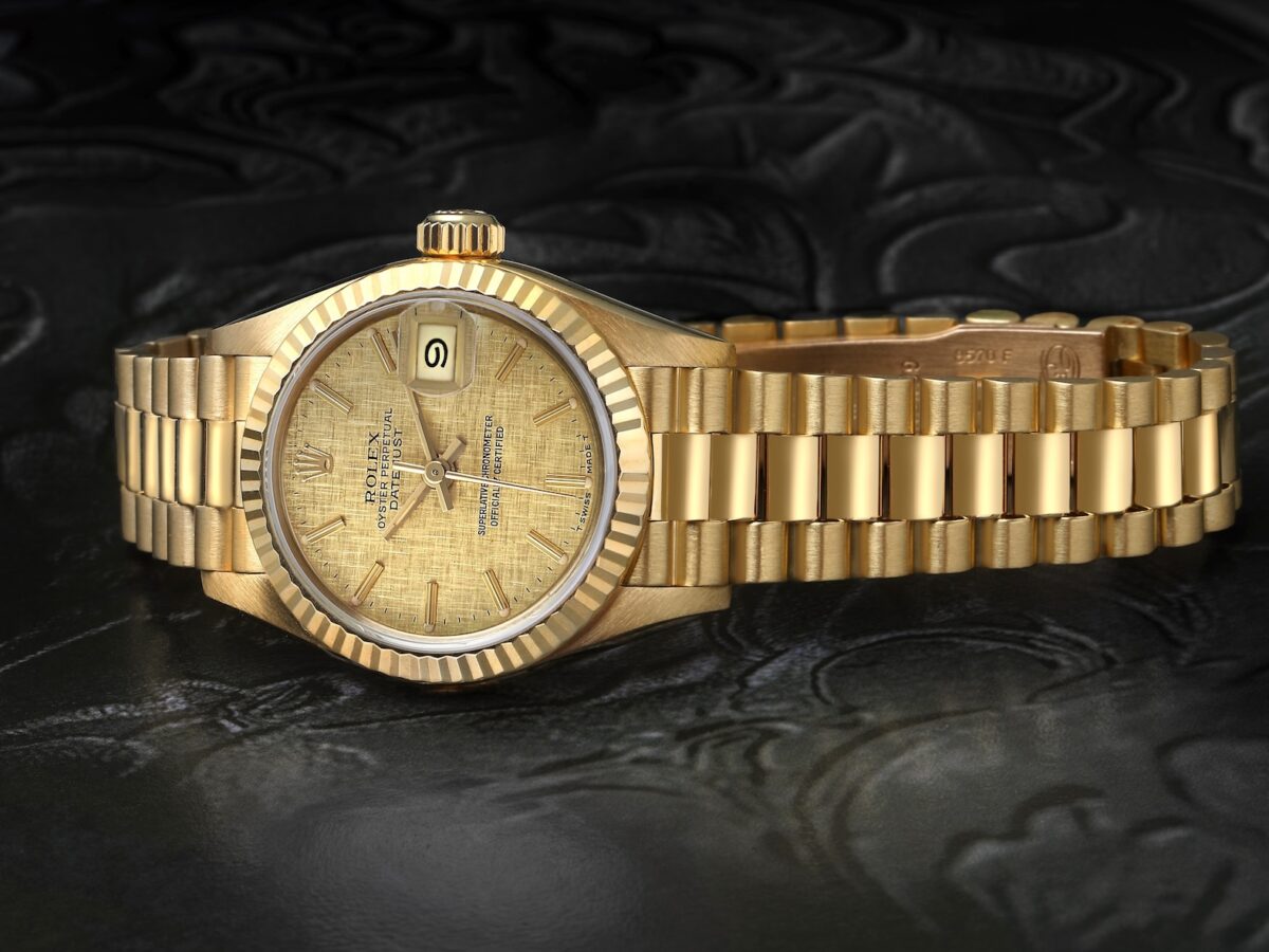 Vintage 26mm Rolex Ladies President Datejust reference 69178 in solid 18k yellow gold featuring a fluted bezel and textured champagne linen dial.