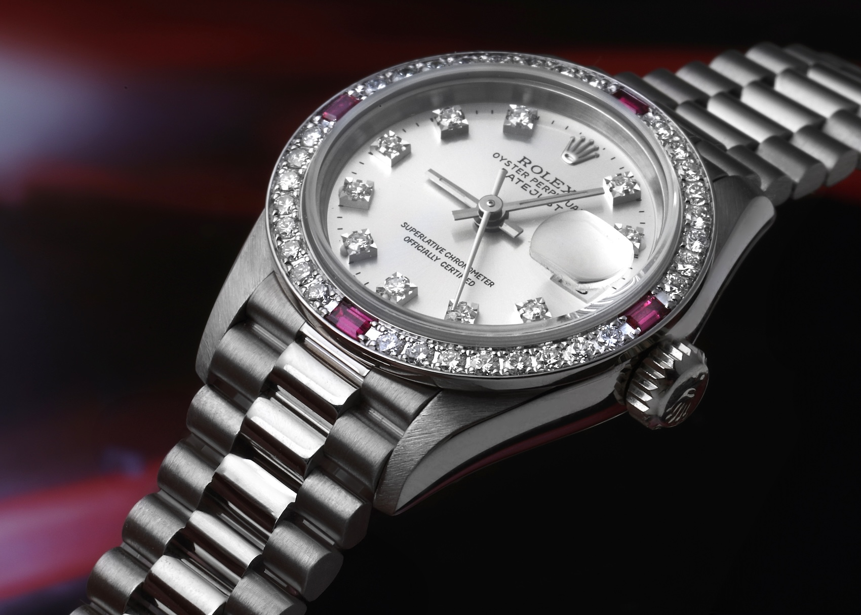 Rolex Ladies President Datejust reference 69069 in 18k white gold featuring a diamond and ruby-set bezel, diamond hour markers, and a concealed Crownclasp President bracelet.