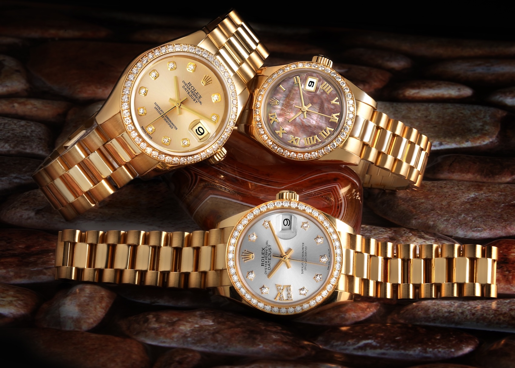 Three 18k yellow gold Rolex Ladies President watches featuring factory diamond bezels and varying dial configurations including champagne, mother-of-pearl, and silver.