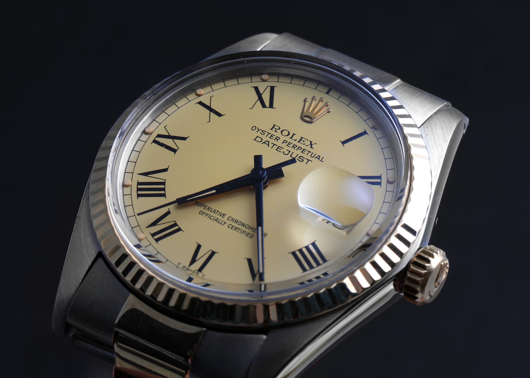 Macro view of a vintage two-tone Rolex Datejust reference 16013 featuring a cream Buckley dial with painted black Roman numerals and matching black hands.