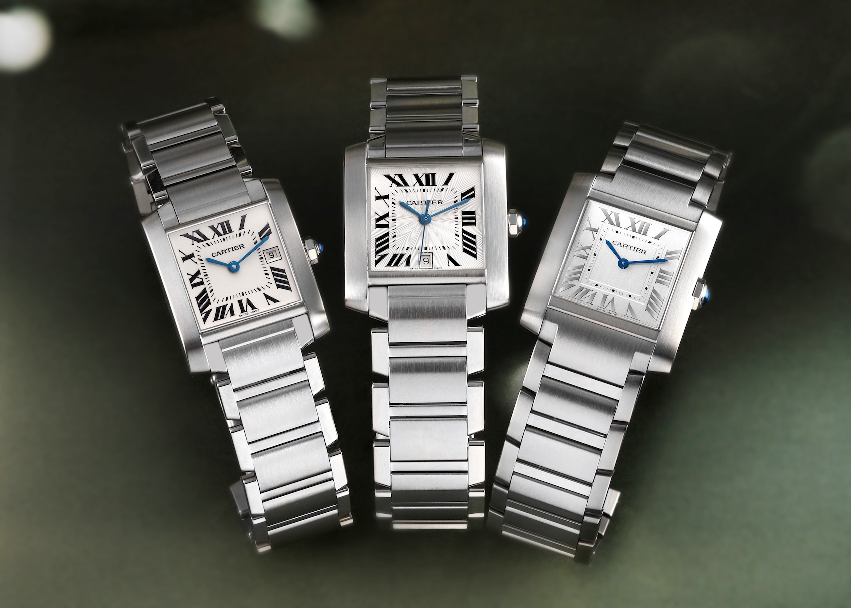 Three stainless steel Cartier Tank Française watches showing the integrated chain-link bracelet, a popular pre-owned Cartier watch under 5000 dollars.