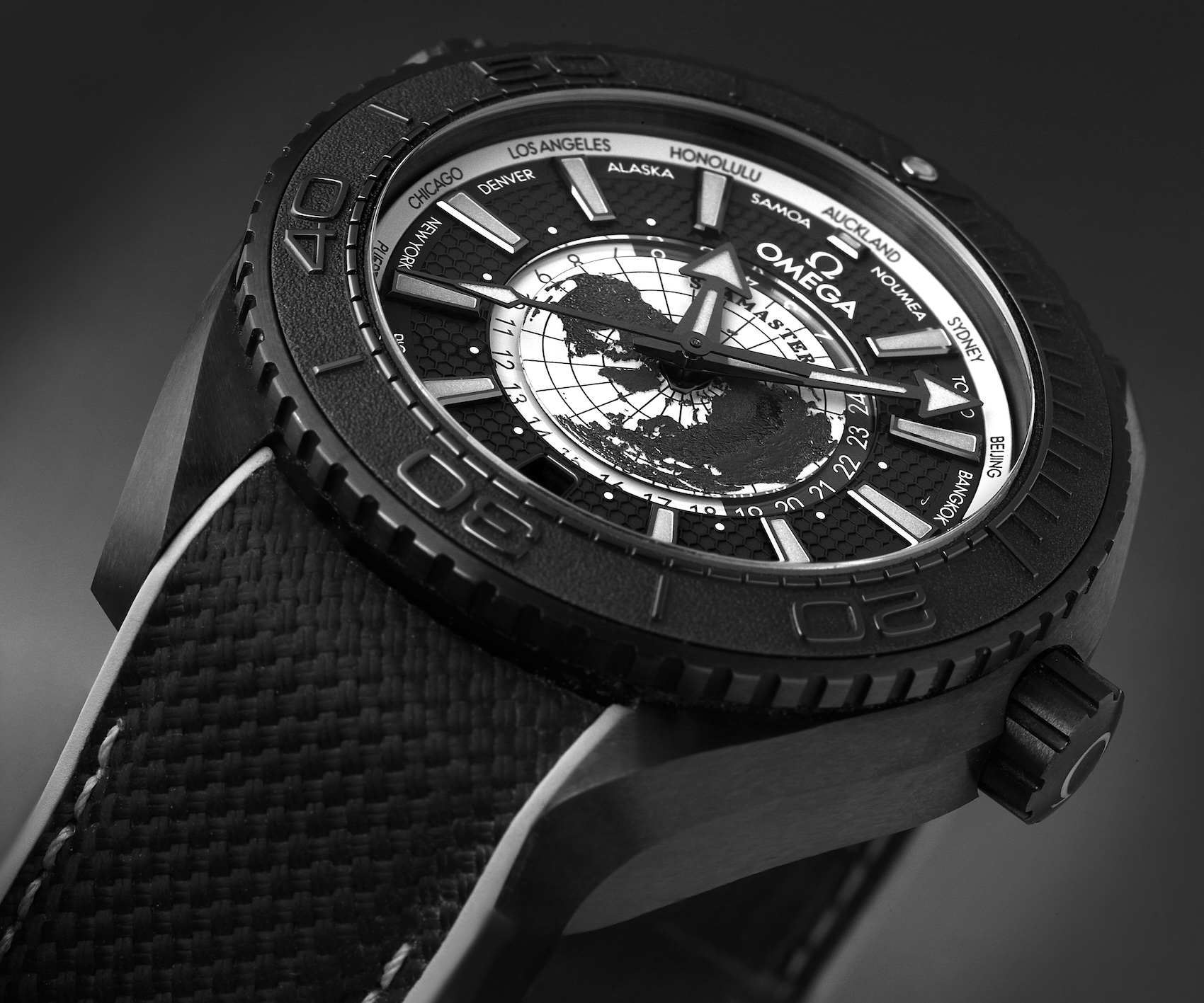 Close-up profile of the Omega Seamaster Planet Ocean 600M Worldtimer 45.5mm brushed black ceramic case, knurled bezel edge, and structured black rubber strap.
